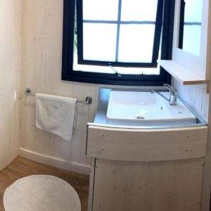 Salle de bain moderne dun hébergement insolite en Auvergne-Rhône-Alpes, bois clair et lumineux.