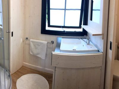 Salle de bain moderne dun hébergement insolite en Auvergne-Rhône-Alpes, bois clair et lumineux.