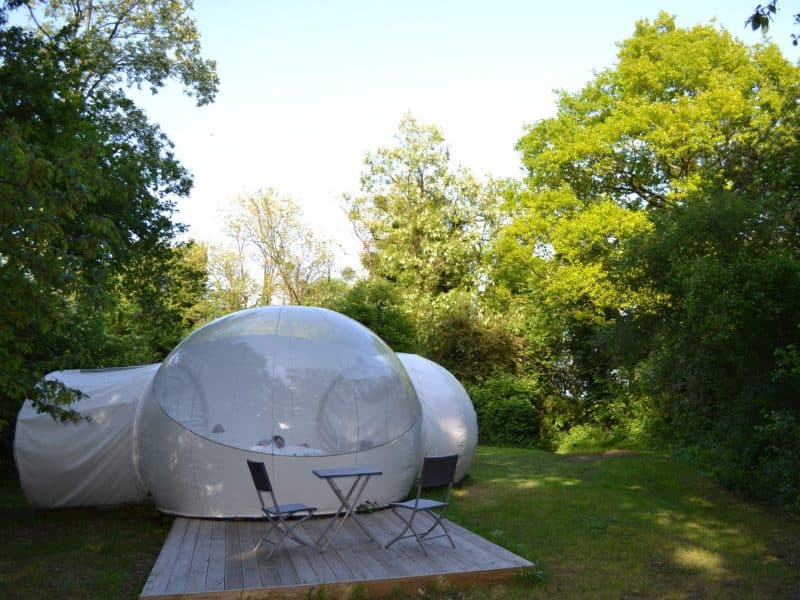Hébergement insolite en bulle transparente, entouré de verdure paisible.