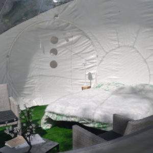 Hébergement insolite en bulle, lit douillet et fauteuils confortables dans un cadre naturel.