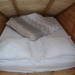 Cabane en bois avec un lit douillet et des coussins moelleux.