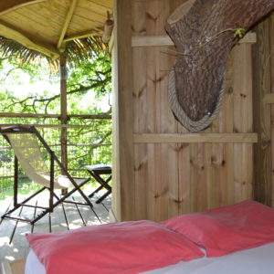 Cabane perchée en bois avec vue sur la nature, lit confortable et décor chaleureux.