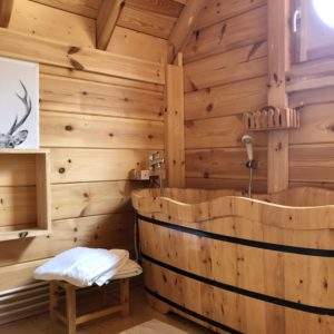 Hébergement insolite en bois avec baignoire en tonneau et décor naturel chaleureux.
