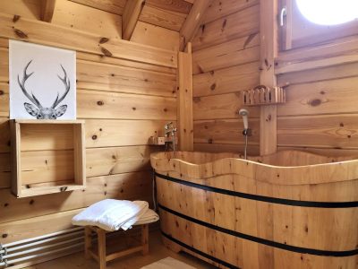 Hébergement insolite en bois avec baignoire en tonneau et décor naturel chaleureux.