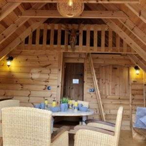 Cabane en bois chaleureuse avec mobilier en rotin et décoration rustique.