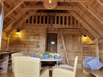 Cabane en bois chaleureuse avec mobilier en rotin et décoration rustique.