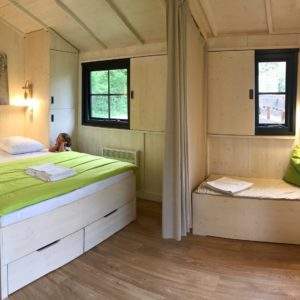 Chalet en bois cosy avec lit double et coin lecture, au cœur de lAuvergne-Rhône-Alpes.