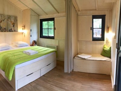 Chalet en bois cosy avec lit double et coin lecture, au cœur de lAuvergne-Rhône-Alpes.