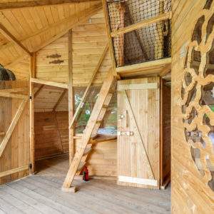 Cabane en bois dans les arbres, avec un intérieur chaleureux et des détails en bois sculpté.