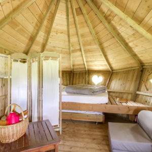 Cabane en bois avec lit douillet et fenêtres en forme de cœur, dans les Pays de la Loire.