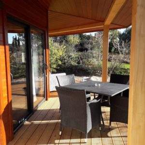 Chalet en bois avec terrasse ensoleillée et mobilier extérieur confortable.