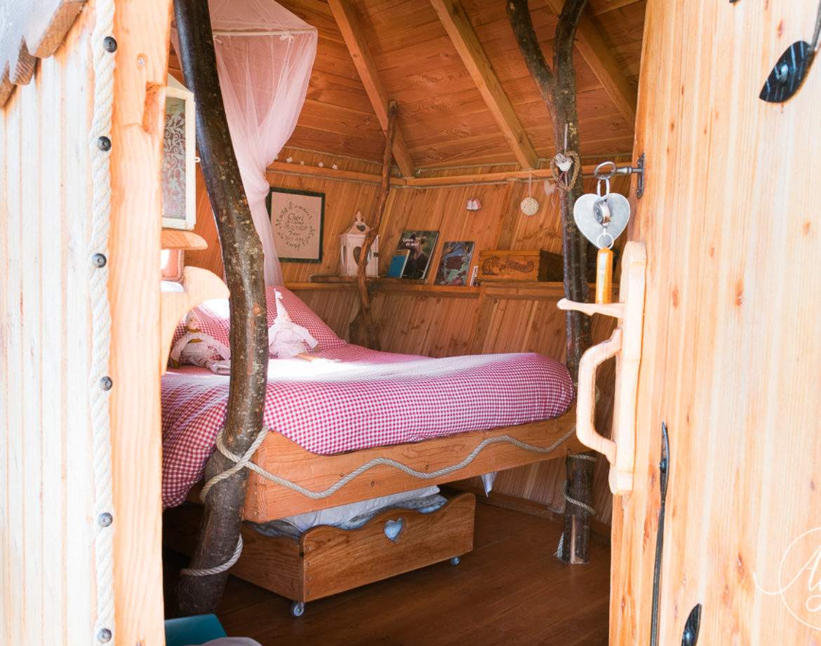 Cabane en bois avec un lit douillet et des branches décoratives à lintérieur.