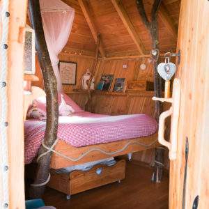 Cabane en bois avec un lit douillet et des branches décoratives à lintérieur.