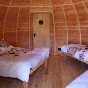Hébergement insolite en Pays de la Loire : cabane en bois avec lits décorés de fleurs.