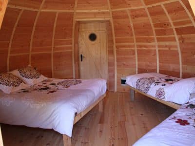 Hébergement insolite en Pays de la Loire : cabane en bois avec lits décorés de fleurs.