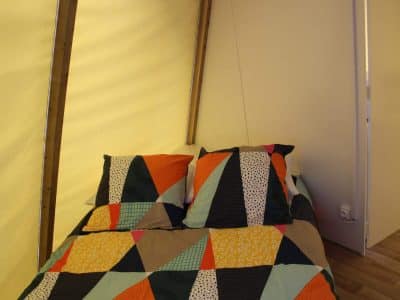 Tente lodge colorée avec un lit douillet et des coussins géométriques.