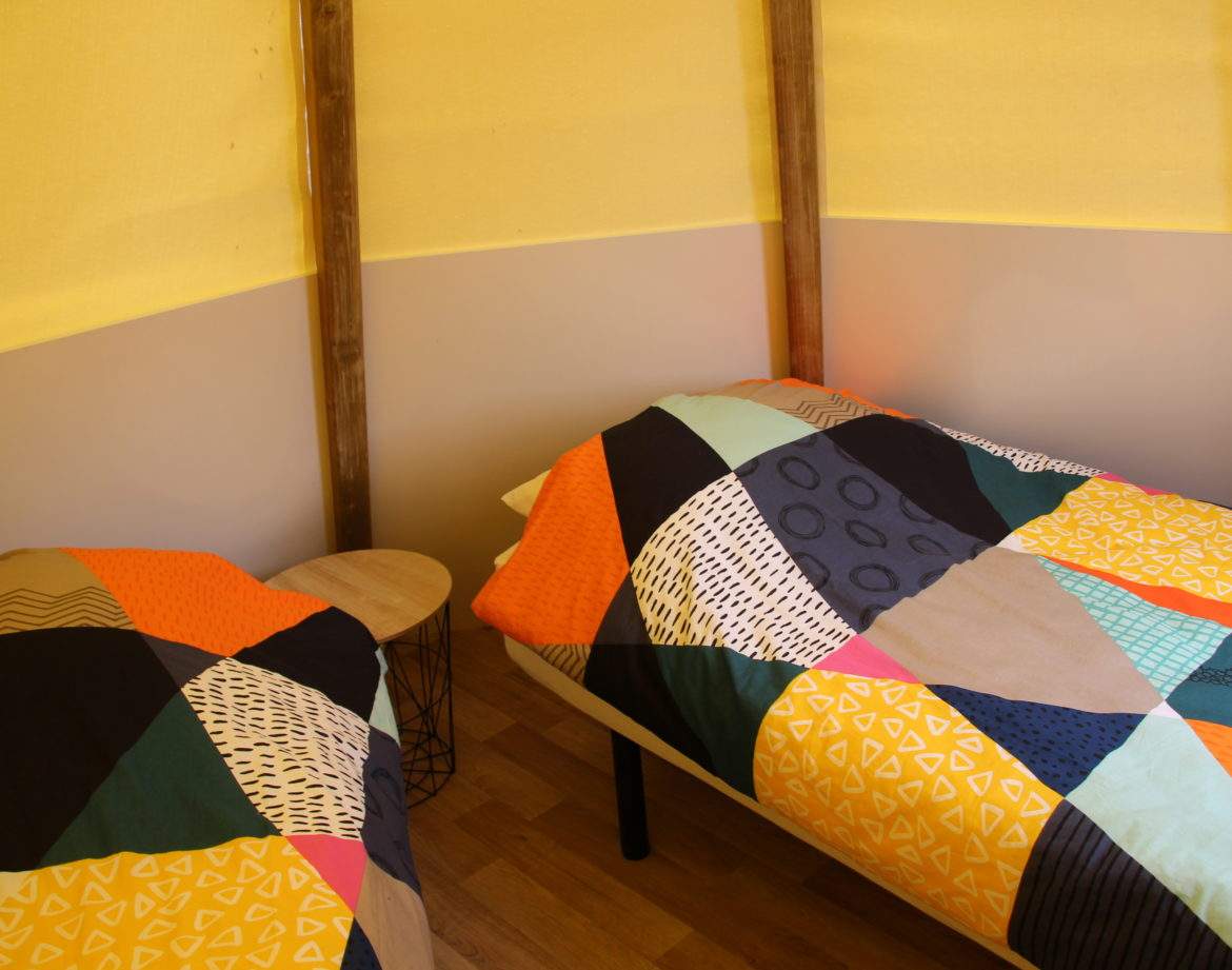 Chalet coloré dans le Pays de la Loire, avec lits aux couvertures géométriques.