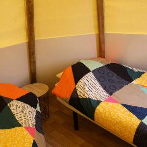 Chalet coloré dans le Pays de la Loire, avec lits aux couvertures géométriques.