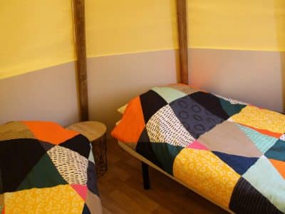 Chalet coloré dans le Pays de la Loire, avec lits aux couvertures géométriques.