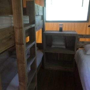 Hébergement insolite en cabane avec lits superposés en bois et ambiance chaleureuse.