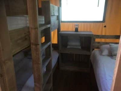 Hébergement insolite en cabane avec lits superposés en bois et ambiance chaleureuse.