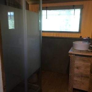 Hébergement insolite en bois avec salle de bain moderne et vue sur la nature.