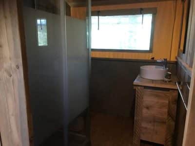 Hébergement insolite en bois avec salle de bain moderne et vue sur la nature.