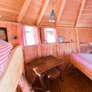 Cabane en bois chaleureuse avec lit douillet et table rustique, Auvergne-Rhône-Alpes.
