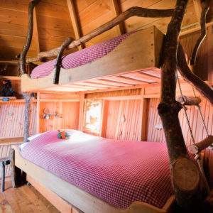Chalet en bois avec lits superposés, ambiance chaleureuse et décor naturel.