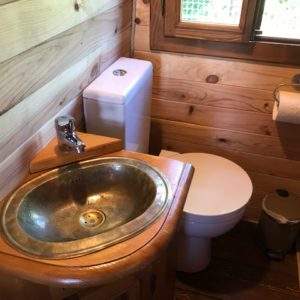 Salle de bain en bois dans un hébergement insolite au Centre, avec lavabo en métal.