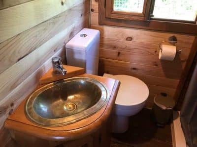 Salle de bain en bois dans un hébergement insolite au Centre, avec lavabo en métal.
