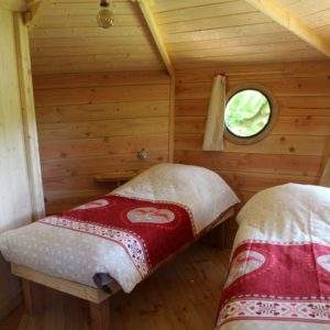 Chalet en bois avec lits jumeaux, décoré de draps rouges à motifs coeurs.