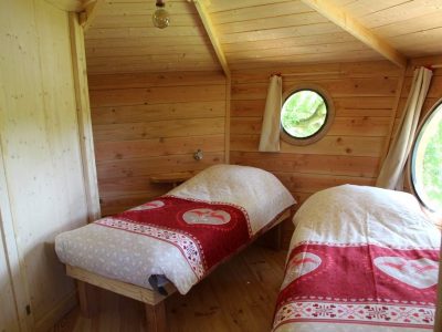 Chalet en bois avec lits jumeaux, décoré de draps rouges à motifs coeurs.