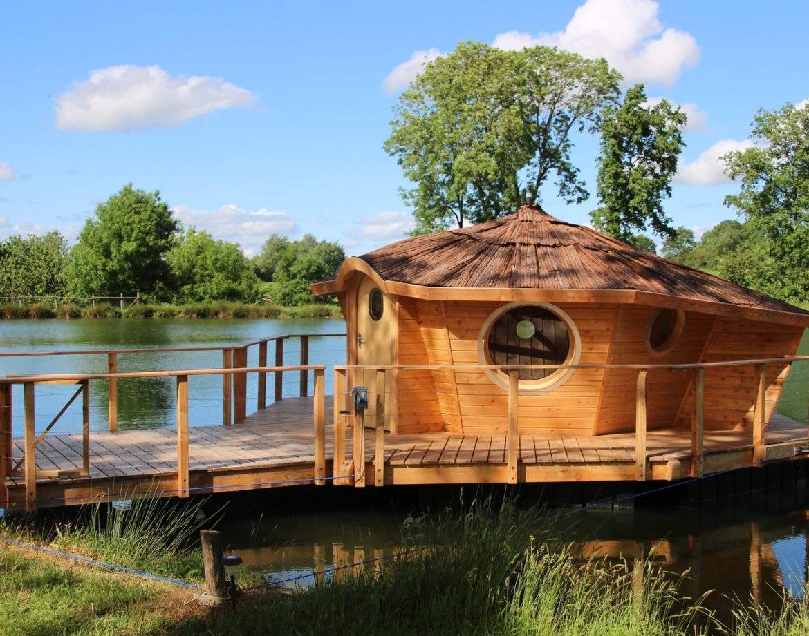 Cabane flottante en bois, avec un toit en chaume, au bord dun étang paisible.