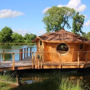 Cabane flottante en bois, avec un toit en chaume, au bord dun étang paisible.