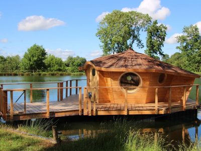 Cabane flottante en bois, avec un toit en chaume, au bord dun étang paisible.
