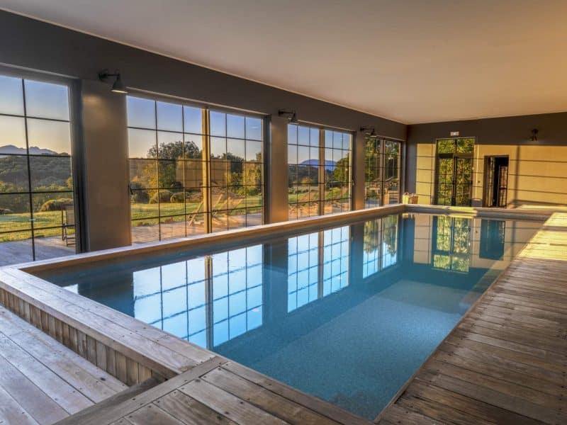 Hébergement de luxe avec piscine intérieure et grandes baies vitrées sur la nature.