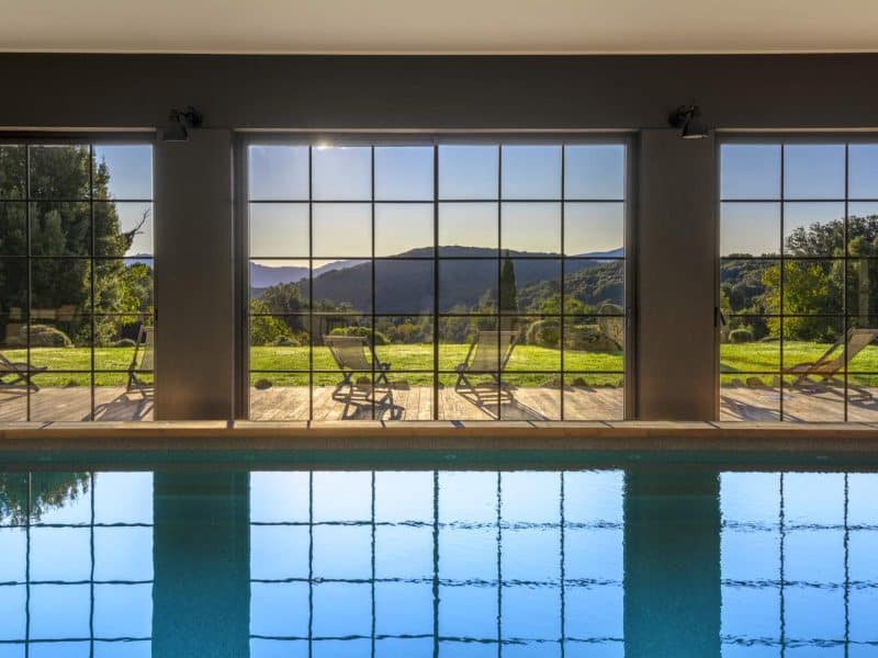 Villa moderne avec piscine intérieure et vue panoramique sur les collines.