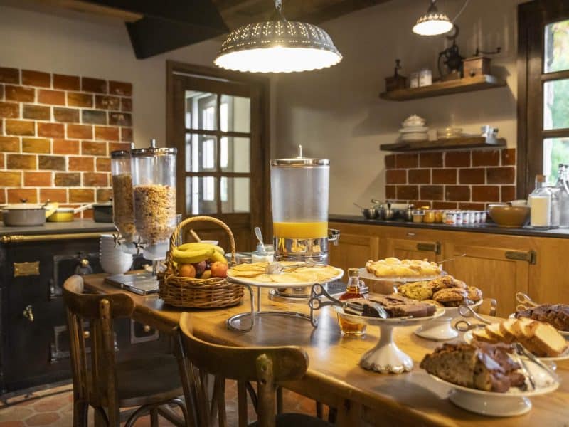 Chambre dhôtes chaleureuse avec un petit-déjeuner copieux sur une table en bois.