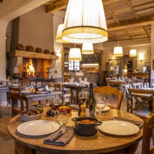 Hébergement insolite en Corse : salle à manger chaleureuse avec cheminée et tables en bois.