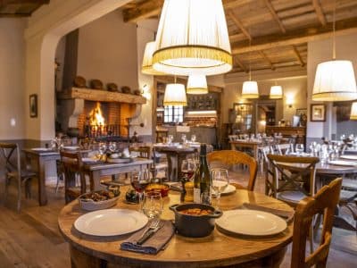 Hébergement insolite en Corse : salle à manger chaleureuse avec cheminée et tables en bois.