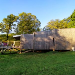 Cabane en bois sur pilotis, entourée de verdure en Basse-Normandie.