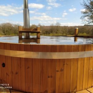 Hébergement insolite en Basse-Normandie avec un jacuzzi en bois sur une terrasse ensoleillée.