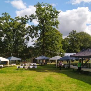 Hébergement insolite en Basse-Normandie, avec tentes et tables sous de grands arbres.