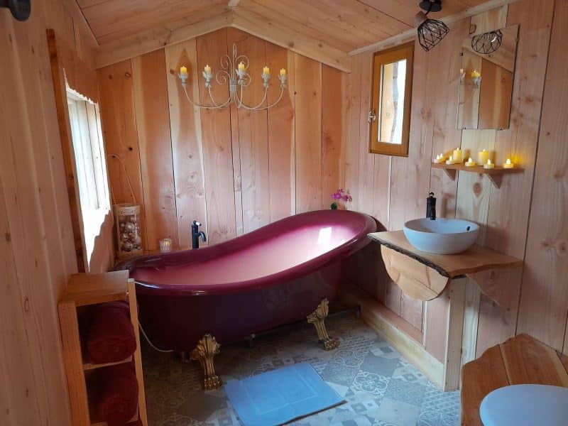 Charmante cabane en bois avec baignoire rétro et ambiance chaleureuse.