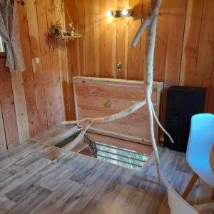 Cabane en bois avec un tronc darbre traversant, ambiance chaleureuse et naturelle.