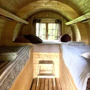 Hébergement insolite en forme de tonneau, intérieur en bois chaleureux avec lits confortables.