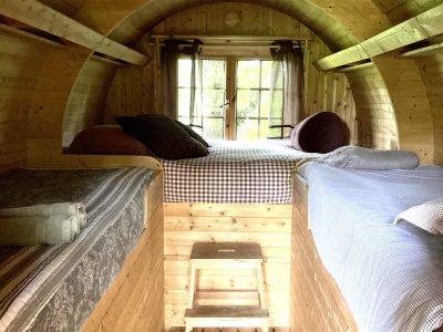 Hébergement insolite en forme de tonneau, intérieur en bois chaleureux avec lits confortables.