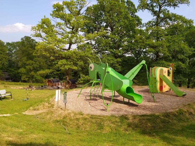 Hébergement en pleine nature avec aire de jeux colorée pour enfants et verdure environnante.