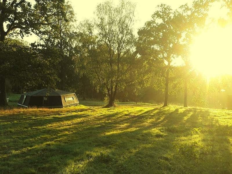 Hébergement insolite en pleine nature, avec un coucher de soleil doré sur le terrain.
